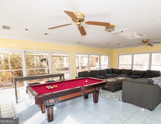 a living room with furniture pool table and windows