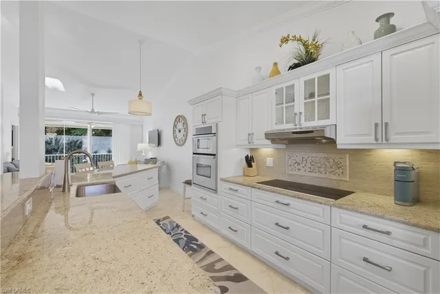 a kitchen with stainless steel appliances kitchen island granite countertop a sink a stove and cabinets