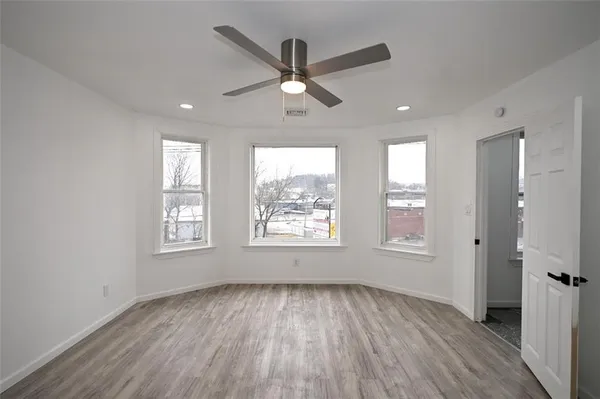 a view of an empty room with a window and wooden floor