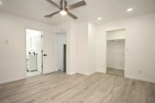 an empty room with wooden floor and a ceiling fan