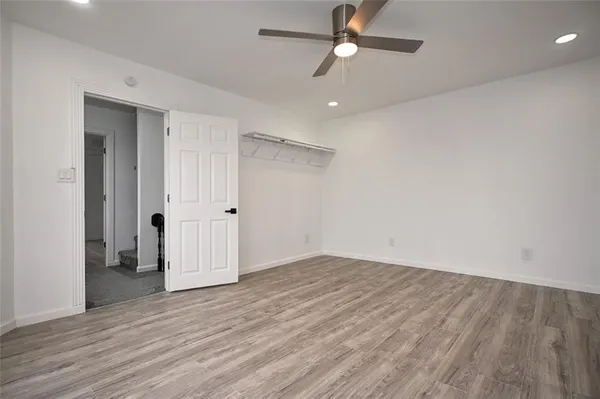 an empty room with wooden floor ceiling fan and windows
