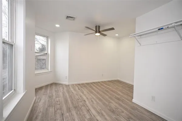 a view of empty room with wooden floor and fan