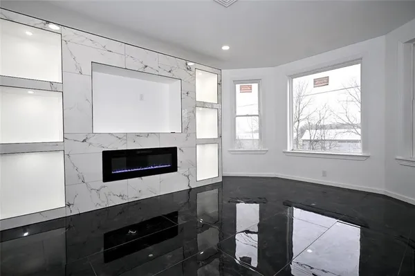 a living room with stainless steel appliances wooden floor and a fireplace