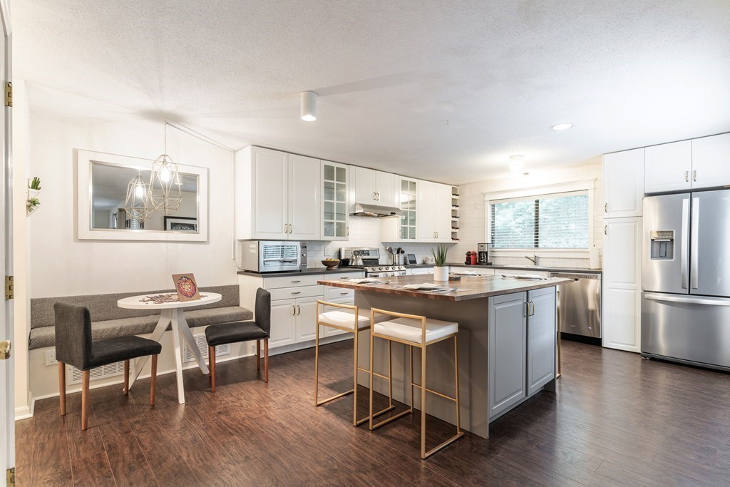 a kitchen with a dining table chairs refrigerator and cabinets