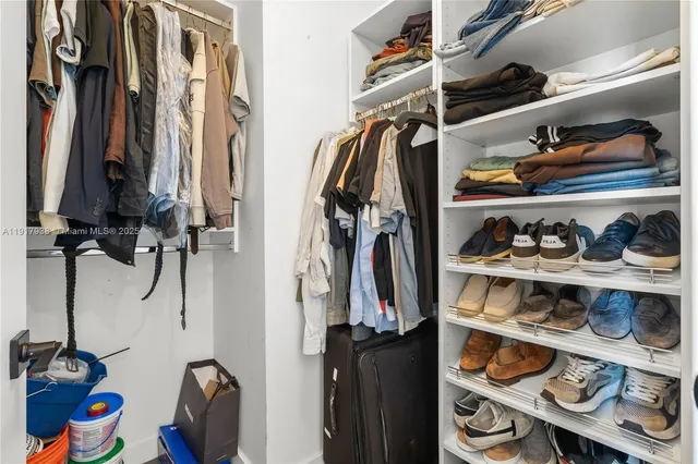 a view of walk in closet with clothes and shoes
