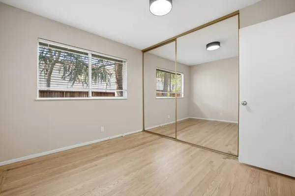a view of empty room with wooden floor and fan