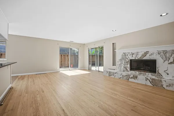 an empty room with windows fireplace and wooden floor