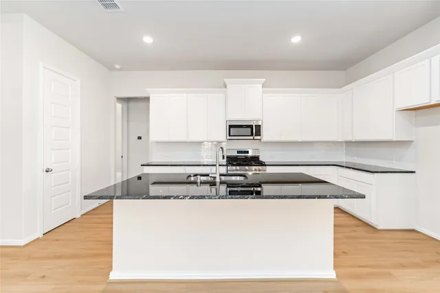 a kitchen with stainless steel appliances granite countertop a stove a sink and a refrigerator