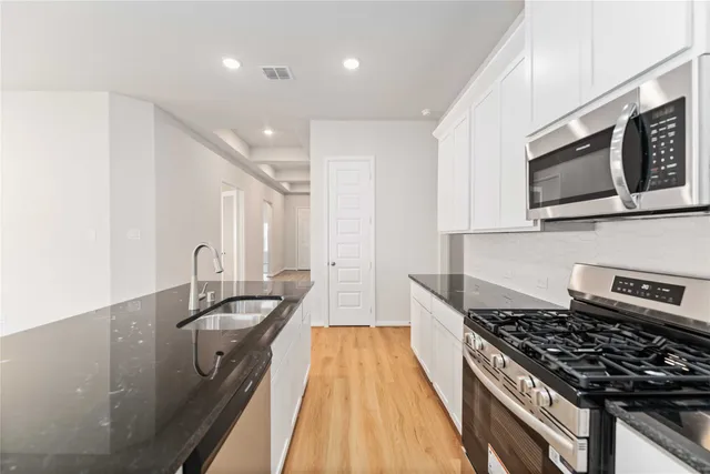 a kitchen with stainless steel appliances a sink a stove and cabinets
