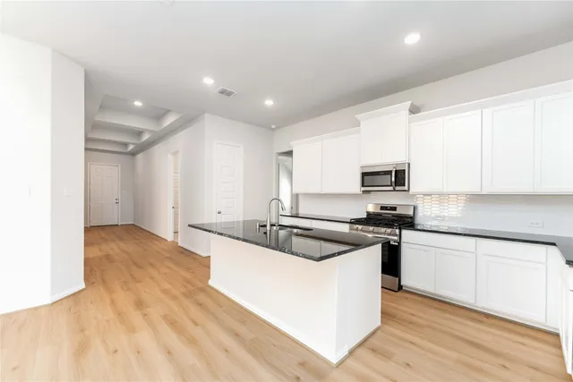 a kitchen with stainless steel appliances granite countertop a sink and white cabinets