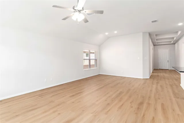 an empty room with wooden floor fan and windows