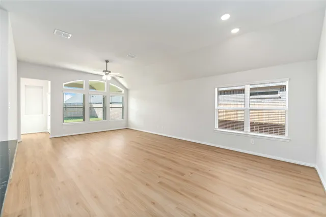 an empty room with wooden floor and windows