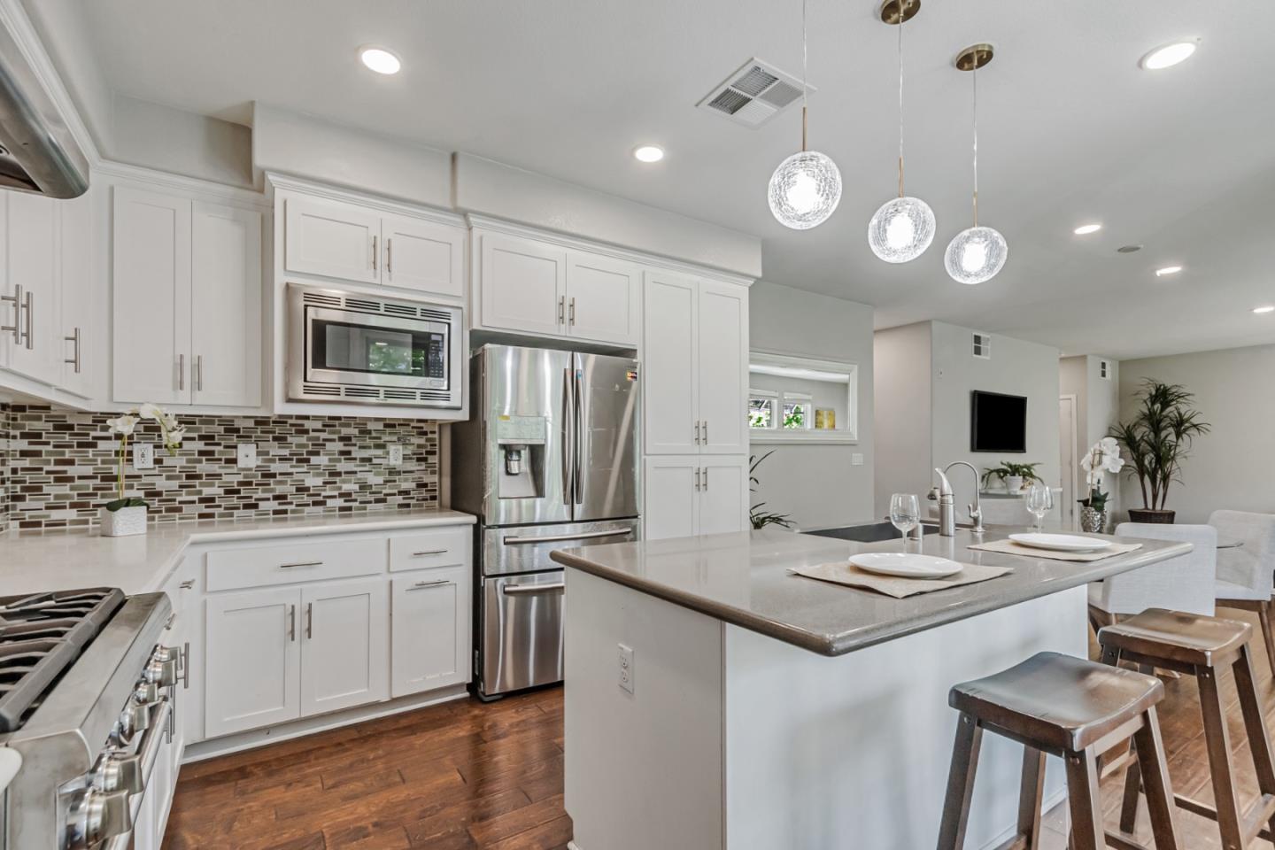 1633 Centre Pointe Drive Milpitas, CA 95035 - Photo 11 of 38 a kitchen with kitchen island granite countertop a sink a stove cabinets and wooden floor