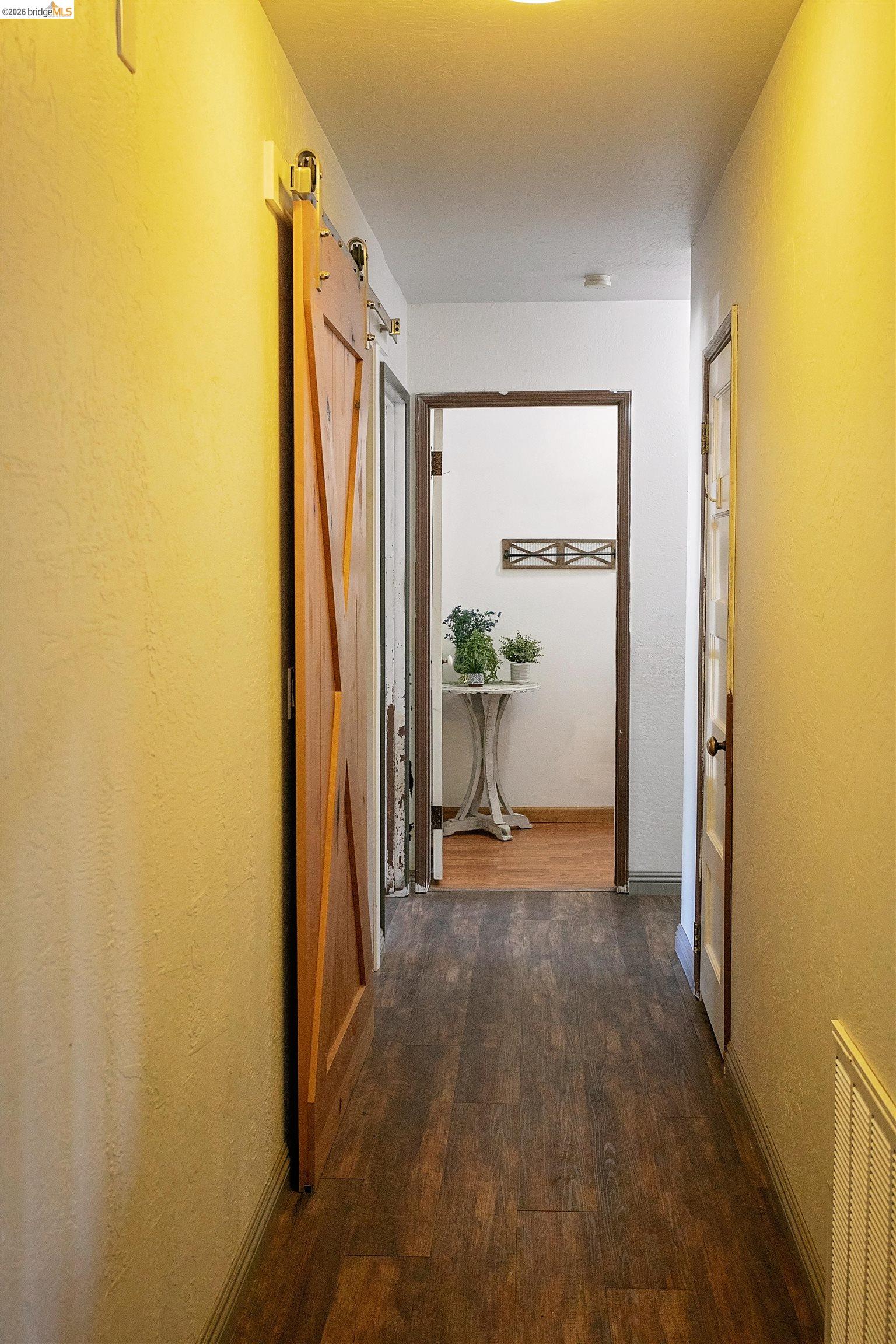 20982 Shaws Flat Road Sonora, CA 95370 - Photo 13 of 26 Hallway featuring wood-finish flooring, a barn door, recessed lighting, and white baseboards