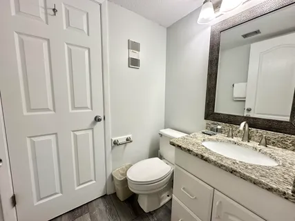 a bathroom with a granite countertop toilet a sink and a mirror