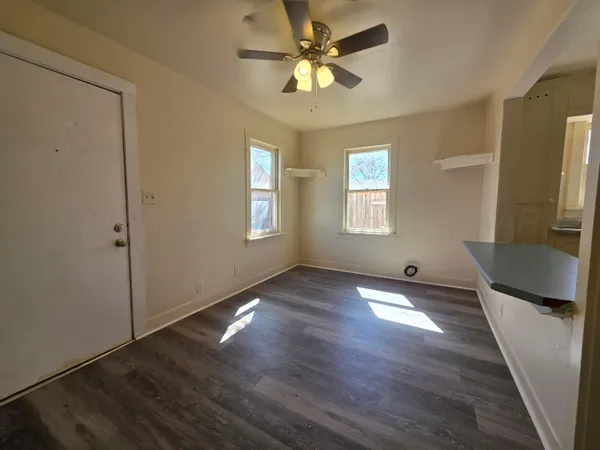 a view of an empty room with window and wooden floor