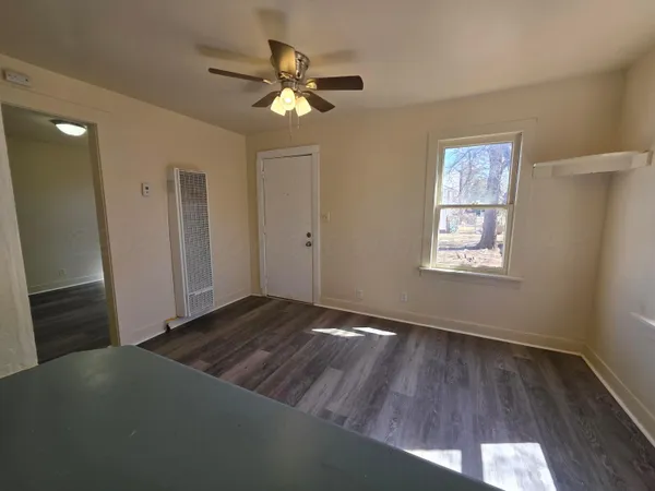 a view of an empty room with wooden floor and a window