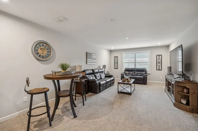 a living room with furniture a flat screen tv and a clock