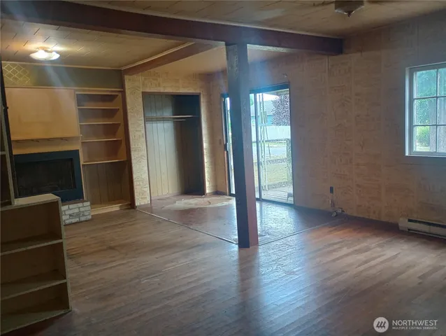 an empty room with wooden floor closet and windows