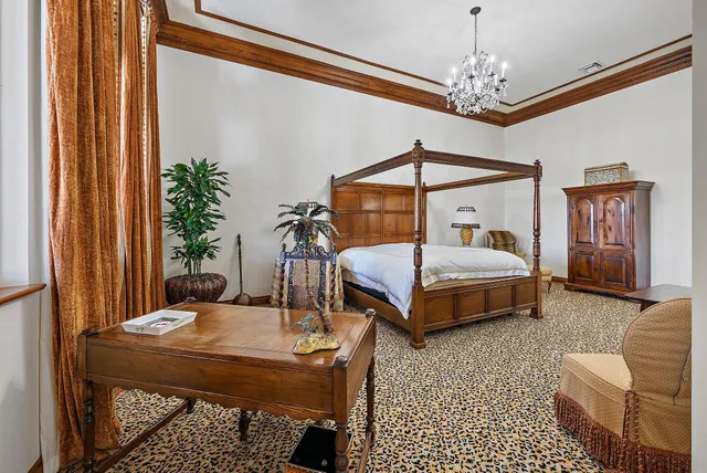 a spacious bedroom with a bed a couch and a chandelier