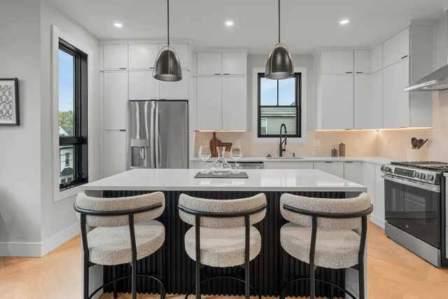 a kitchen with stainless steel appliances granite countertop a sink a stove and chairs