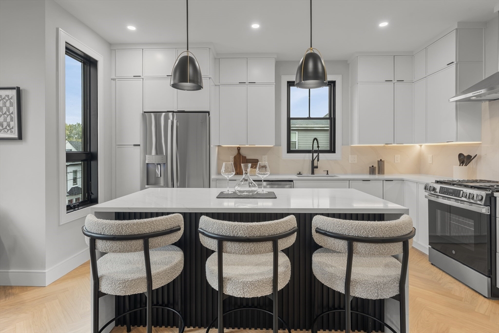 a kitchen with stainless steel appliances granite countertop a sink a stove and chairs