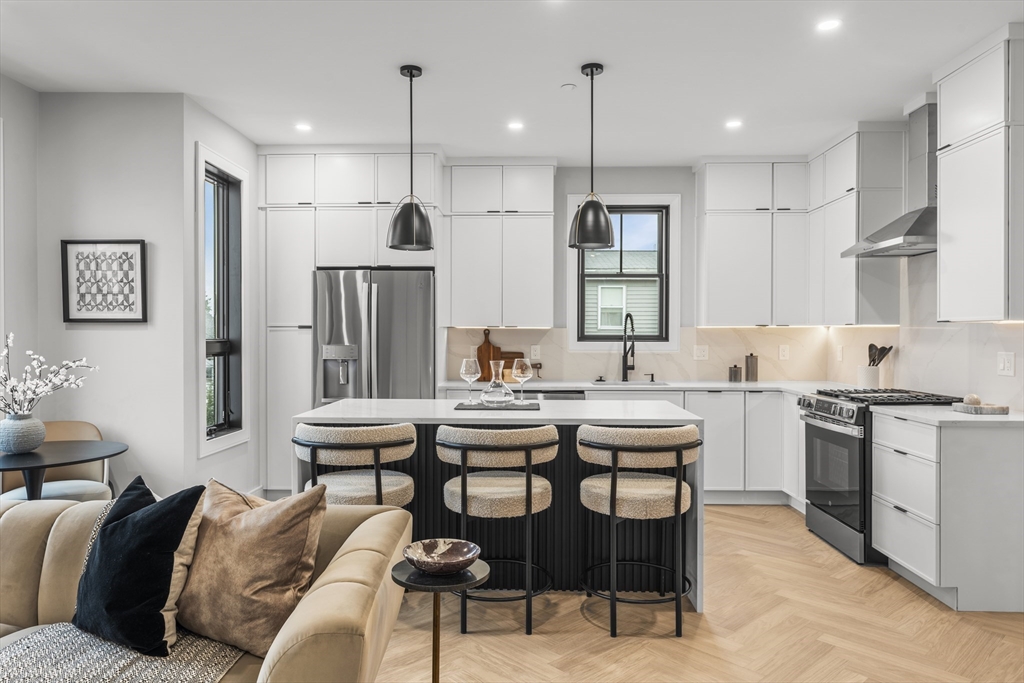 106 Moore Street, Unit 8 Boston, MA 02128 - Photo 9 of 9 a kitchen with stainless steel appliances kitchen island granite countertop a sink and a refrigerator