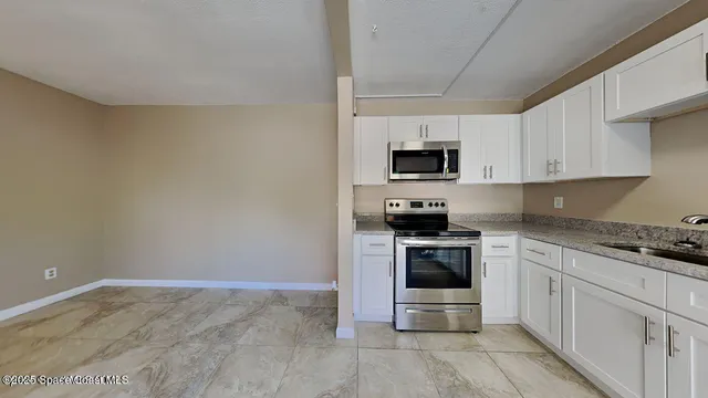 a kitchen with granite countertop a stove top oven and cabinets