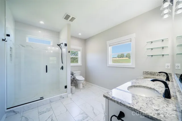a bathroom with a granite countertop sink and a toilet