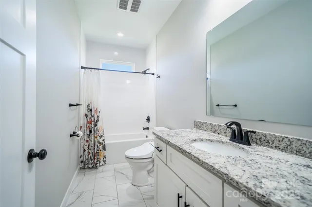 a bathroom with a granite countertop sink a toilet and shower