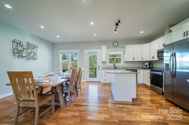 a kitchen with stainless steel appliances kitchen island granite countertop a table chairs refrigerator and a sink