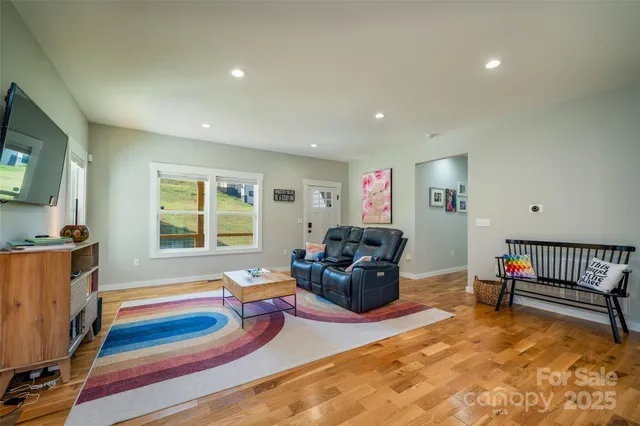 a living room with furniture a flat screen tv and a refrigerator