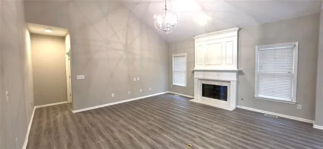 an empty room with wooden floor fireplace and windows