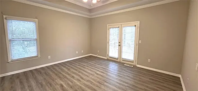 an empty room with wooden floor and windows