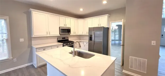 a kitchen with stainless steel appliances granite countertop a sink dishwasher a refrigerator and a stove with wooden floor