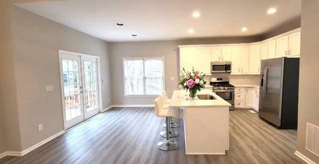 a kitchen with stainless steel appliances kitchen island granite countertop a refrigerator a stove top oven a sink and dishwasher with wooden floor