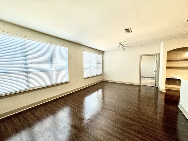 a view of an empty room with window and wooden floor