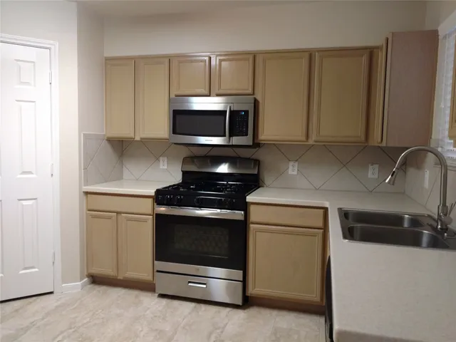 a kitchen with stainless steel appliances granite countertop a stove microwave and sink