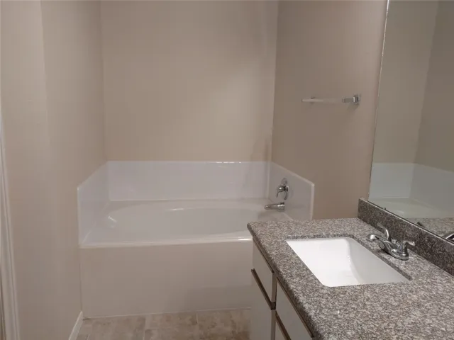 a bathroom with a granite countertop bathtub sink vanity and mirror