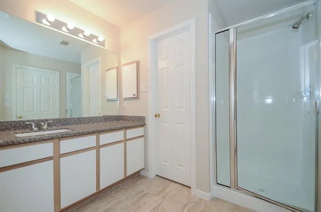 a bathroom with a granite countertop sink a mirror and a shower