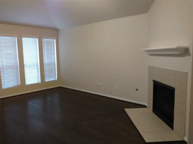 a view of an empty room with wooden floor and a fireplace