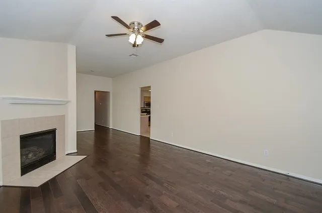 a view of an empty room with wooden floor and a fireplace
