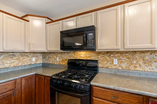 a kitchen with stainless steel appliances granite countertop white cabinets and black stove top oven with granite countertops