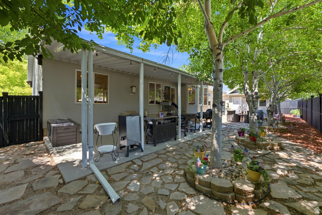 5196 Rodeo Circle Oakley, UT 84055 - Photo 44 of 57 Expansive flagstone patio with a covered outdoor living area, bordered by mature trees and a dark-toned privacy fence