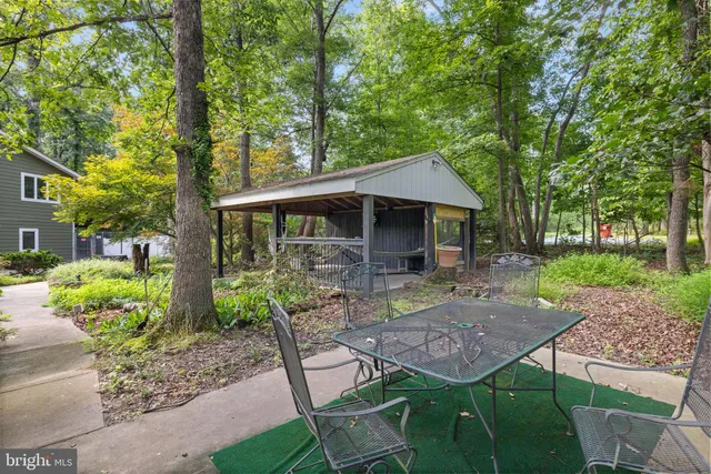 a view of a patio with table and chairs potted plants and large tree