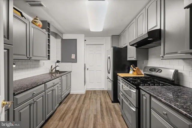 a kitchen with stainless steel appliances granite countertop a stove a sink and a refrigerator
