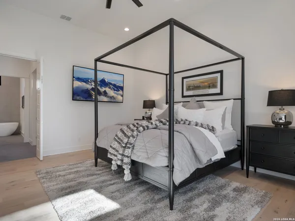 a bedroom with a bed table and flat screen tv