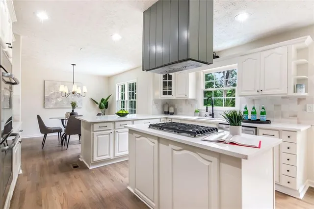 a kitchen with kitchen island white cabinets and stainless steel appliances