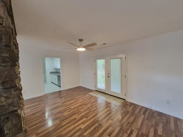a view of an empty room with window and wooden floor