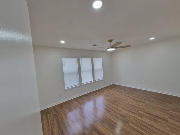 a view of empty room with wooden floor and fan